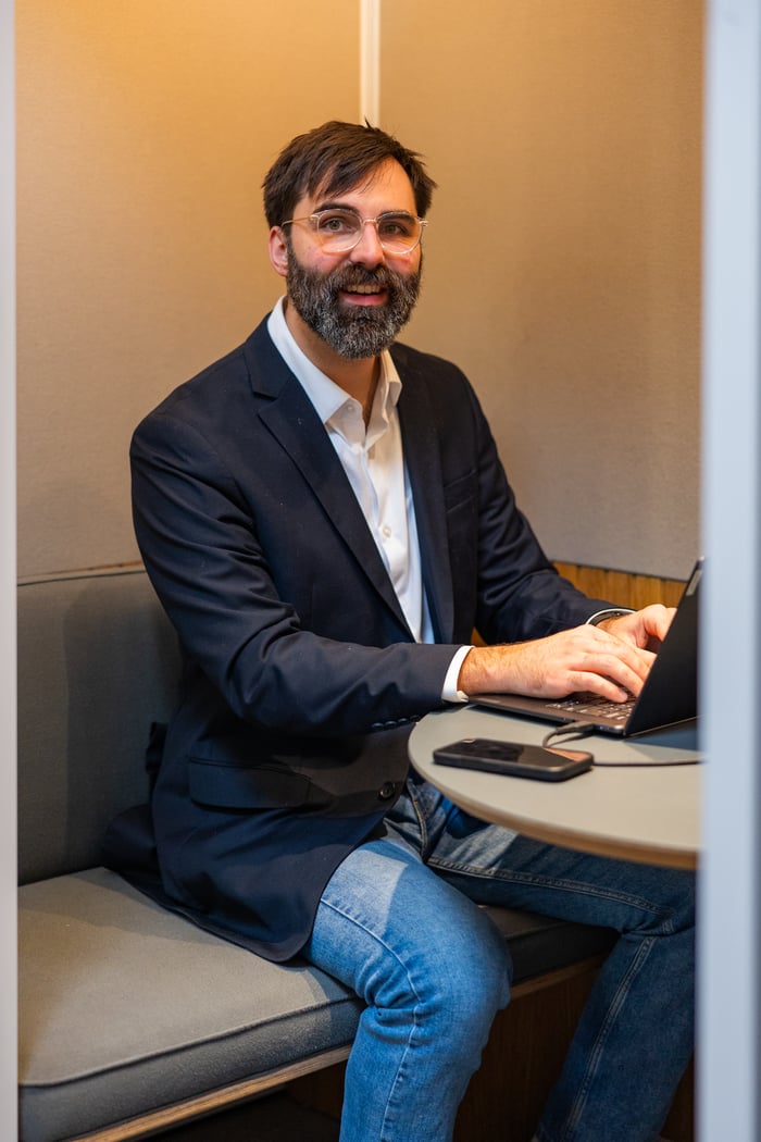 A Compoze Labs engineer smiling beside a whiteboard with a laptop